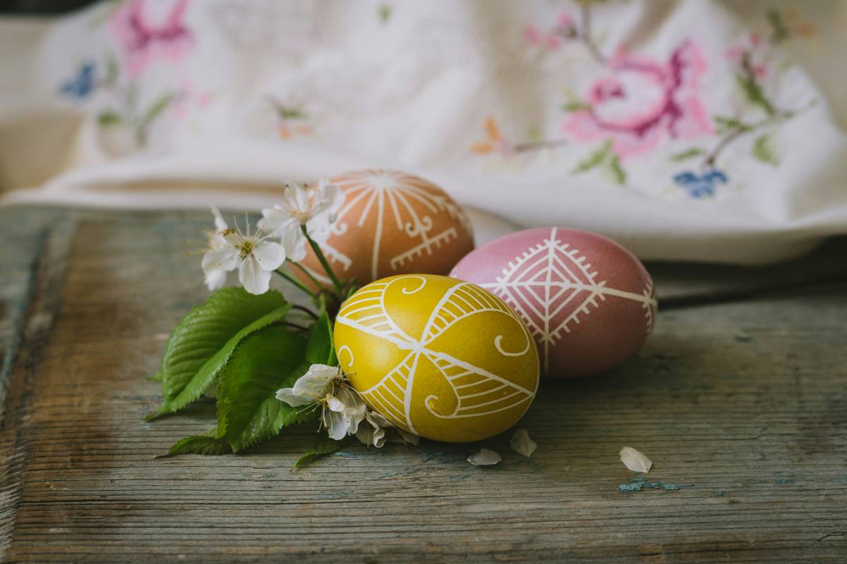 easter home decorating ideas featuring a rustic wooden tray with pastel eggs, fresh tulips, and linen napkins on a farmhouse table